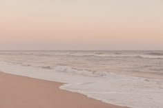 two people walking on the beach with surfboards