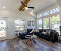 a living room with wood flooring and large windows in the ceiling, along with an l - shaped couch