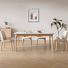 a dining room with white walls and wooden flooring is pictured in this image, there are three chairs around the table