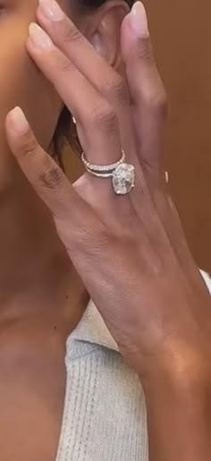 a close up of a person wearing a ring on their finger and holding something in the other hand