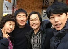 four people posing for a photo in front of a store