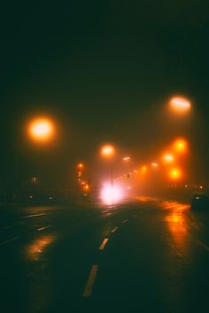 street lights shine brightly in the dark on a foggy night