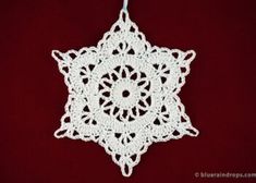 a white crocheted ornament hanging on a red background