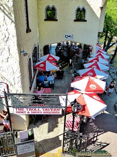 an overhead view of tables and umbrellas in front of a building with people walking by