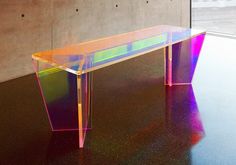 a glass table sitting on top of a black floor next to a wall and window