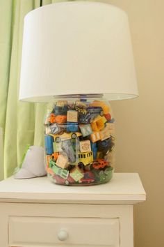 a jar filled with toys sitting on top of a white dresser next to a lamp