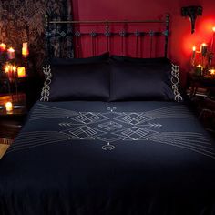 a bed with black comforter and candles in the background