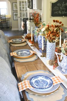 a long table with blue and white plates on it, candlesticks and flowers