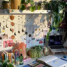 a laptop computer sitting on top of a desk next to a wall covered in plants