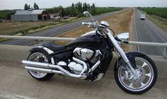 a black motorcycle parked on the side of a road next to a highway with houses