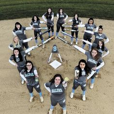 a group of women standing in the middle of a baseball field with bats and balls