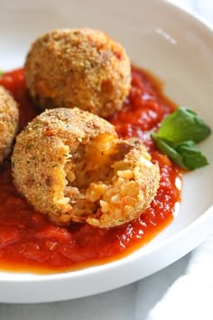 three balls of meatballs in tomato sauce on a white plate