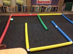 a child playing with an inflatable ball and stick set on the floor next to bookshelves