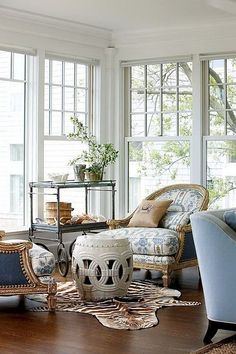 a living room filled with lots of furniture next to large windows and wooden flooring