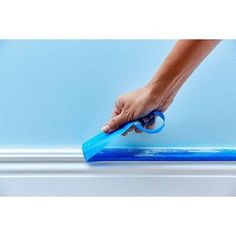 a person is using a blue roller to paint a wall with light blue walls and white trim