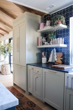 a kitchen with white cabinets and blue tile backsplashing on the countertops