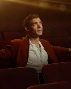 a man is sitting in an empty theater with his arms spread out and eyes wide open