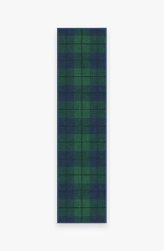 a green and blue plaid wall hanging on a white wall with a black frame in the middle