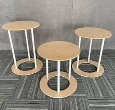 three round tables sitting on top of a wooden floor next to each other in front of a wall