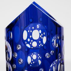 a blue glass vase with white dots and circles on the top, sitting in front of a white background