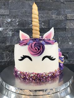 a white cake with purple frosting and a unicorn's face