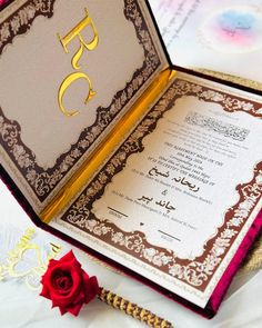 an open book with arabic writing on it and a rose in the middle next to it