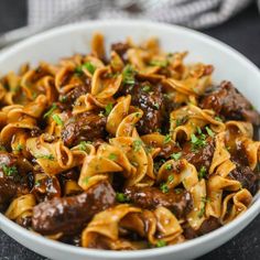 a white bowl filled with pasta and meat