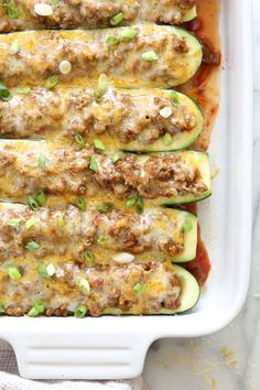 stuffed zucchini boats in a white casserole dish with meat and cheese