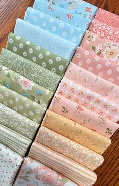 a bunch of different types of fabric on a wooden table with one folded in half