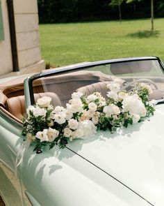 flowers are placed on the hood of an old car