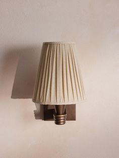 a lamp that is on the side of a wall with a light shade over it