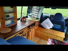 an interior view of a camper van with wood furniture and blue upholstered seats