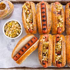 hot dogs with mustard, onions and ketchup on a tray next to condiments