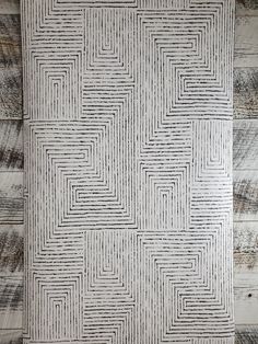 a white and black pattern on the wall in front of a wood paneled floor