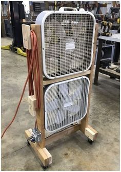 an old fan sitting on top of a wooden stand in a room filled with tools