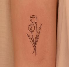 a single flower tattoo on the left side of the arm, with two tulips growing out of it