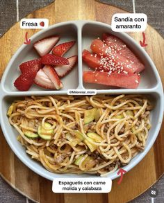 a plate with strawberries, spaghetti and other food items in it on a wooden platter