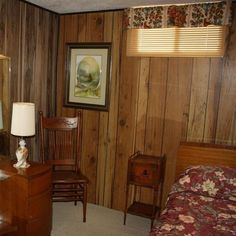 a bedroom with wood paneling and a desk in the corner next to a bed