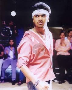 a man standing in front of a crowd wearing a pink shirt and white headband