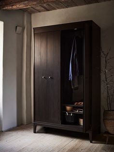 an armoire in the corner of a room with a basket and towel hanging on it