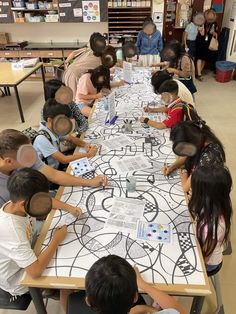 a group of children sitting at a table with paper and magnifying glasses on it