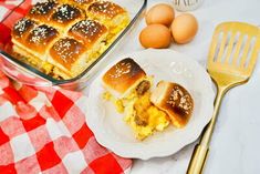 a plate with some food on it next to an egg and cheese roll in a casserole dish