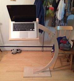 a laptop computer sitting on top of a wooden chair in front of a wall mounted shelf