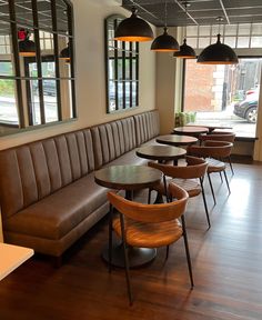 tables and chairs are lined up in a restaurant with large windows on either side of the wall