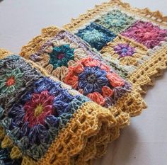 two crocheted squares sitting on top of a table next to eachother