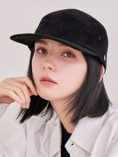 a woman with black hair wearing a white shirt and a black hat, posing for the camera