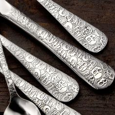 four silver spoons sitting on top of a wooden table