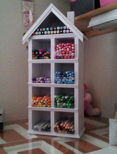 a doll house with lots of colorful crayons on the shelves in front of it