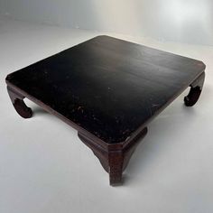 an old wooden table sitting on top of a white floor with no one around it