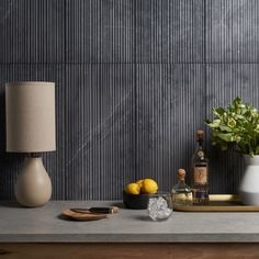 a table topped with a vase filled with lemons next to a lamp